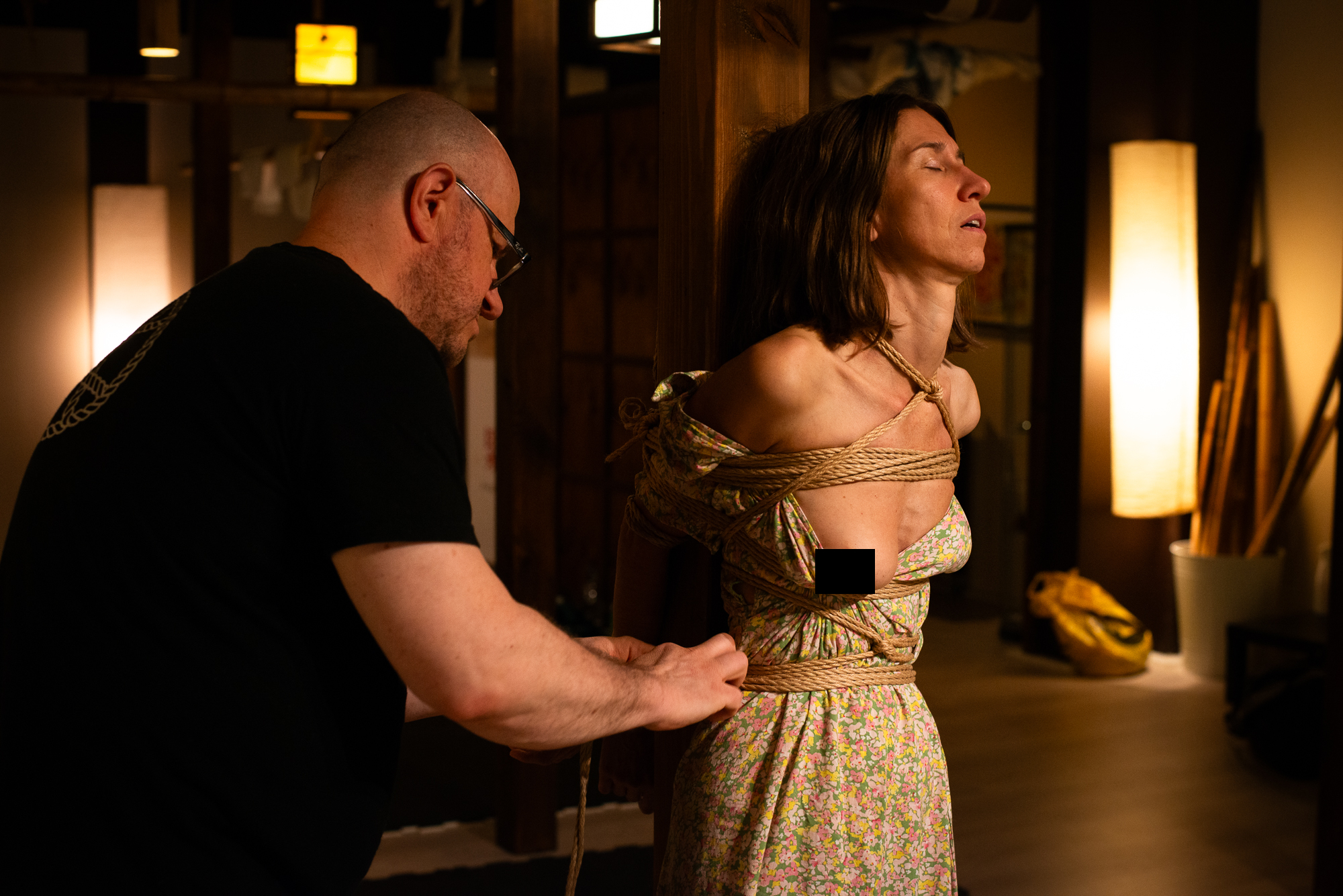 a man is tying a woman to the hashira (vertical pole)