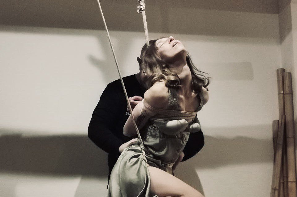 Rope bottom arching backwards while being tied in a Kinbaku session