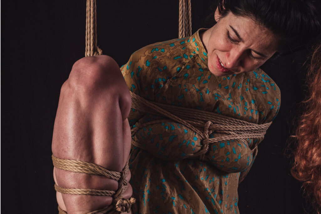 Rope bottom looking down at her body while being tied in a Kinbaku session